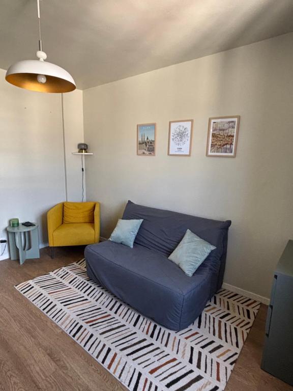 sala de estar con sofá azul y silla amarilla en Appart du Théâtre, en Caen