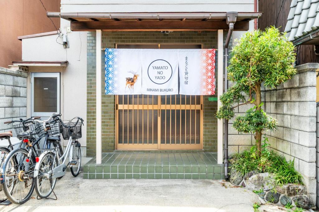 a front door of a house with bikes parked outside at 大和の宿 Minamibukuro in Nara