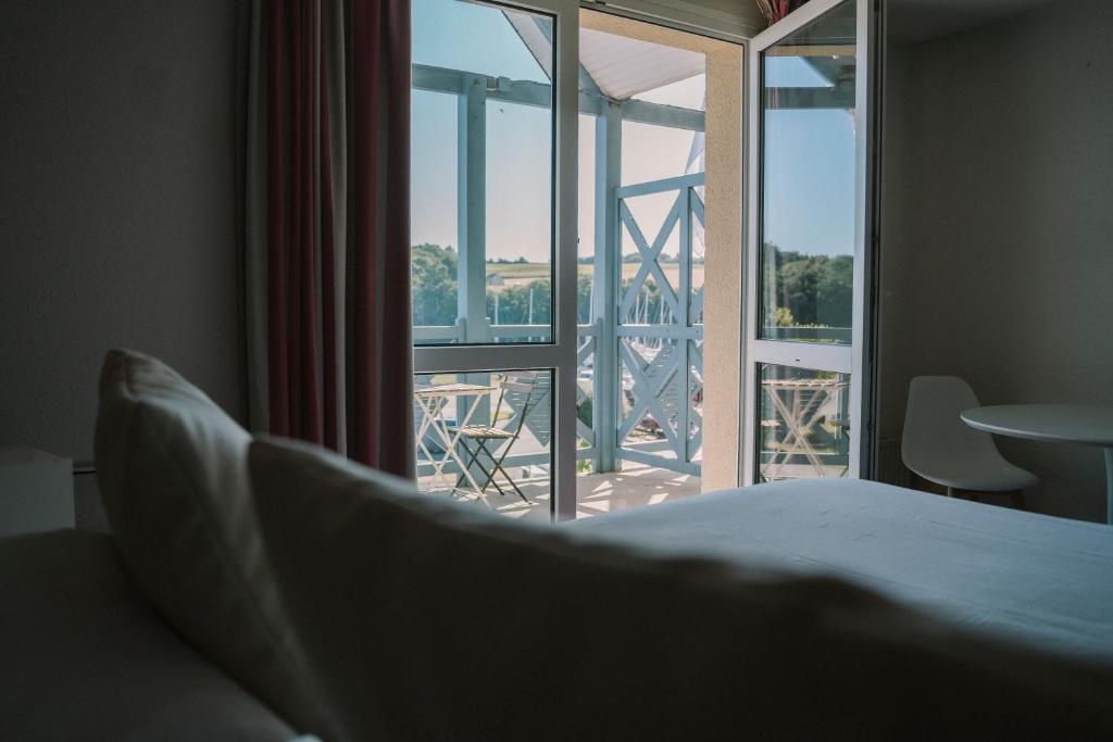 een slaapkamer met een bed en uitzicht op een balkon bij Hotel Aigue Marine in Tréguier