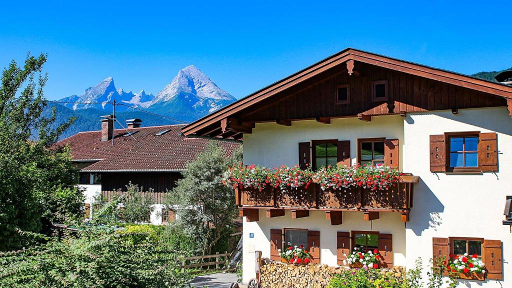 a house with flowers on the balcony with mountains in the background at FEWO Wimmer in Bischofswiesen