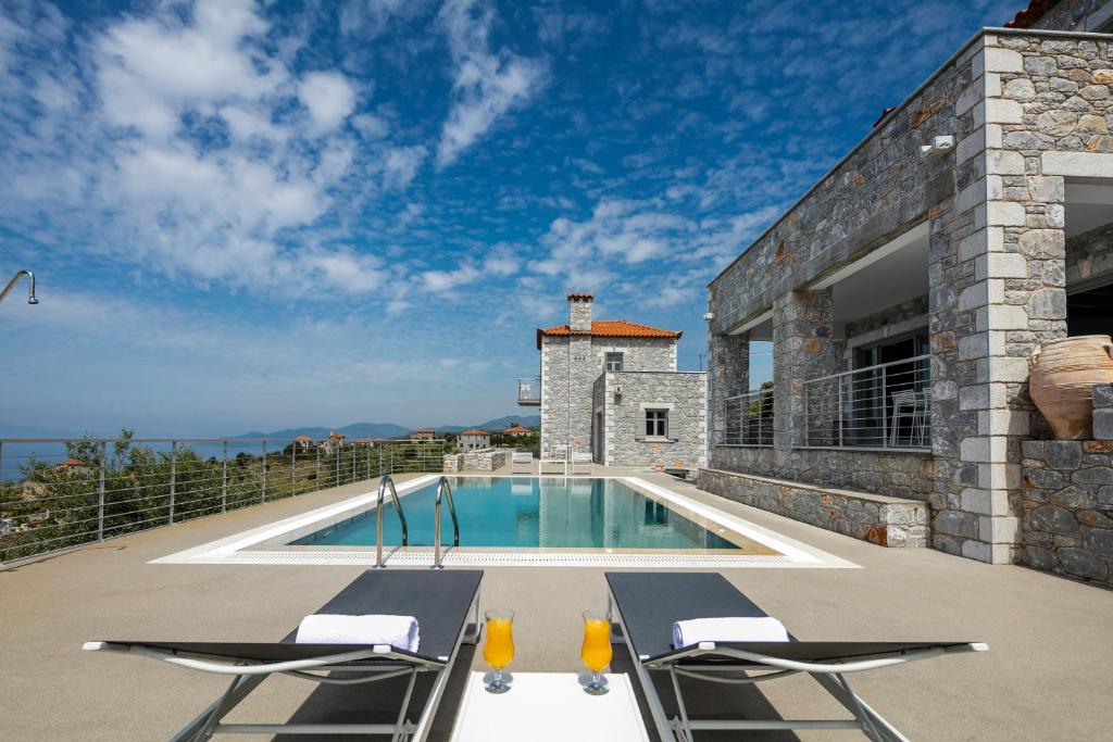 a villa with a swimming pool and two chairs at Asanti Villas in Lévktron