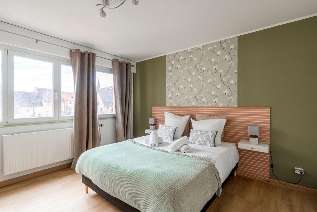 a bedroom with a large bed with green walls at Le Petit Schatz in Colmar