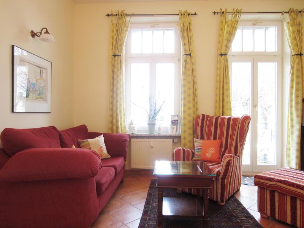 a living room with a red couch and two chairs at Ferienwohnung Dünenstraße in Kühlungsborn