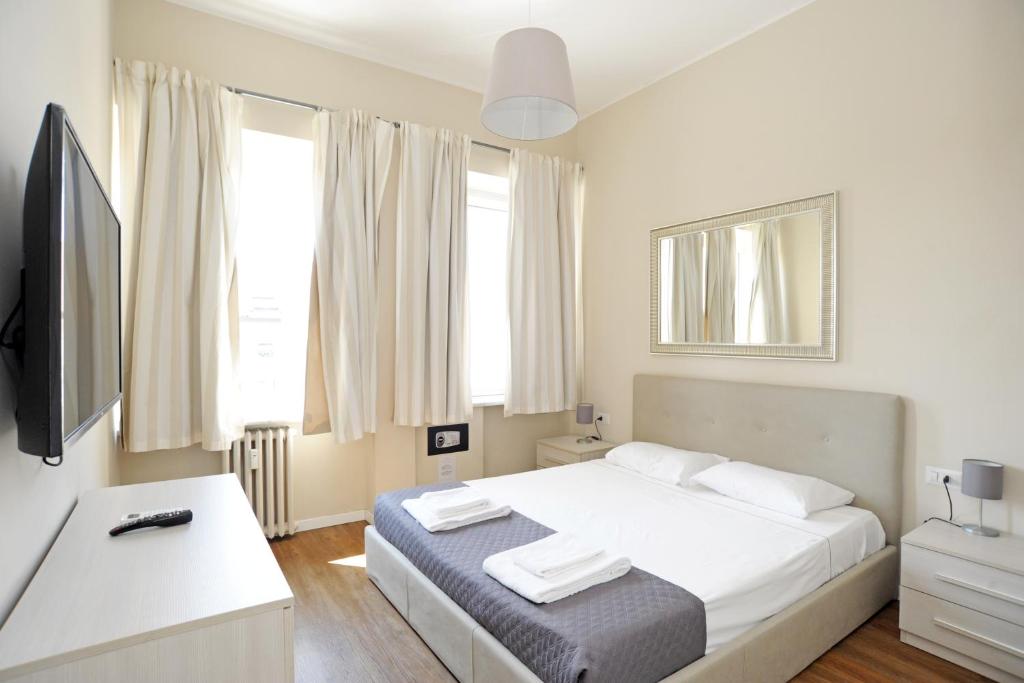 een witte slaapkamer met een bed en een televisie bij Via Torino Apartment 3 in Milaan