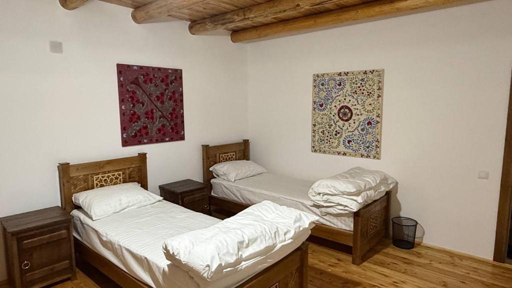 a room with three beds and a painting on the wall at Nurata Eco Guesthouse in Yangiqishloq