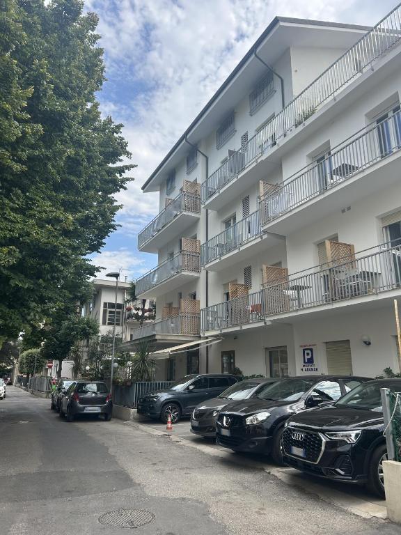 a parking lot in front of a building with parked cars at Hotel Abamar in Rimini