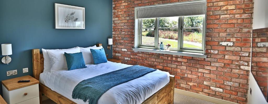 a bedroom with a brick wall and a bed at Cock O' Barton in Coddington