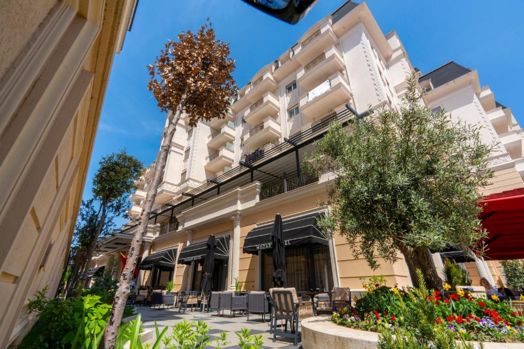ein Gebäude in einer Straße mit Tischen und Stühlen in der Unterkunft Hotel Mozart in Shkodra