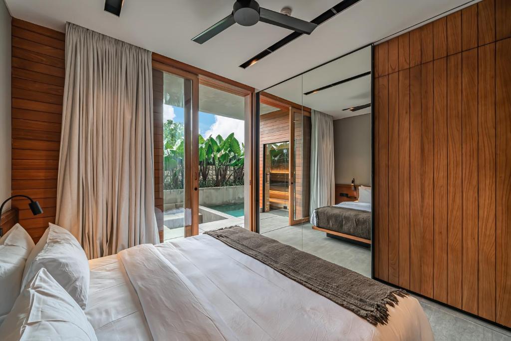 a bedroom with a large bed and a large window at Body Factory Lifestyle Residence Uluwatu in Uluwatu