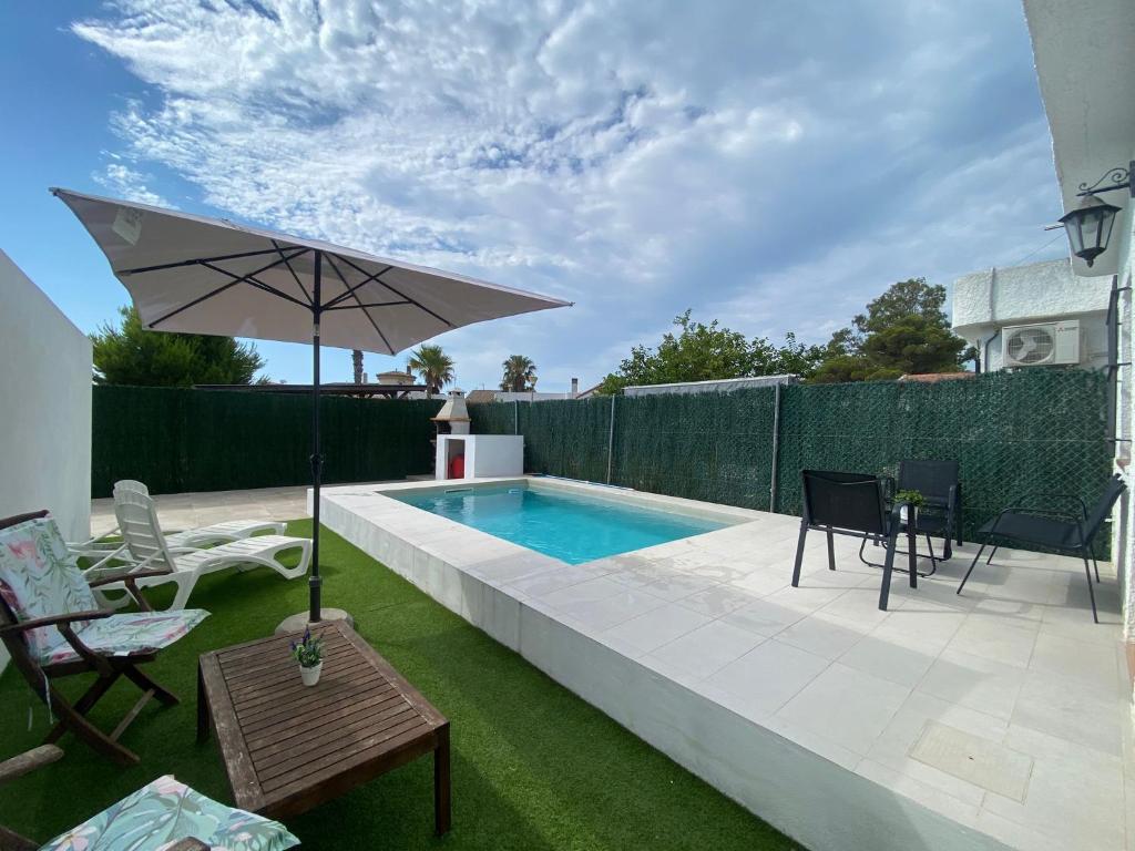 einen Hinterhof mit Pool und Sonnenschirm in der Unterkunft Casa Beatriz in Riumar