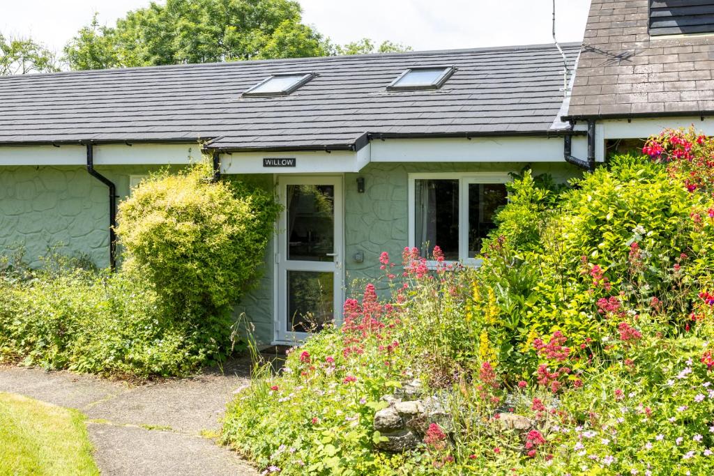 a green house with flowers in front of it at Willow at Gorslwyd - Sound Retreat in Aberporth