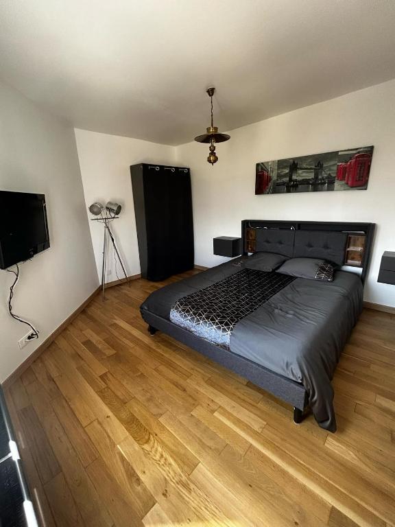 Un dormitorio con una cama y un televisor de pantalla plana. en Esprit Londonien - WIFI - TV -, en Bracquemont