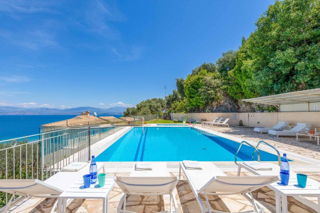 a swimming pool with white tables and chairs next to the water at Villa Irida in Apraos