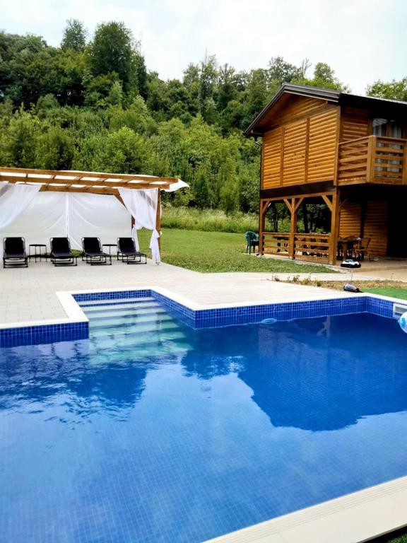 a large swimming pool in front of a cabin at Vikendica Čardak in Srebrenik