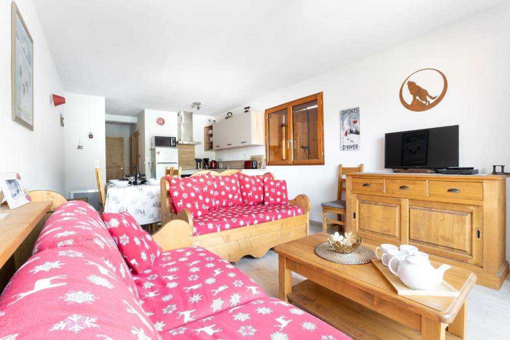 a living room with two red couches and a tv at Terrasse avec vue sur les montagne pour 6 in La Joue du Loup
