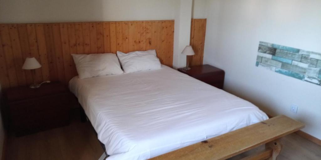 a bedroom with a bed with white sheets and two lamps at Casa do Meio in Nadadouro