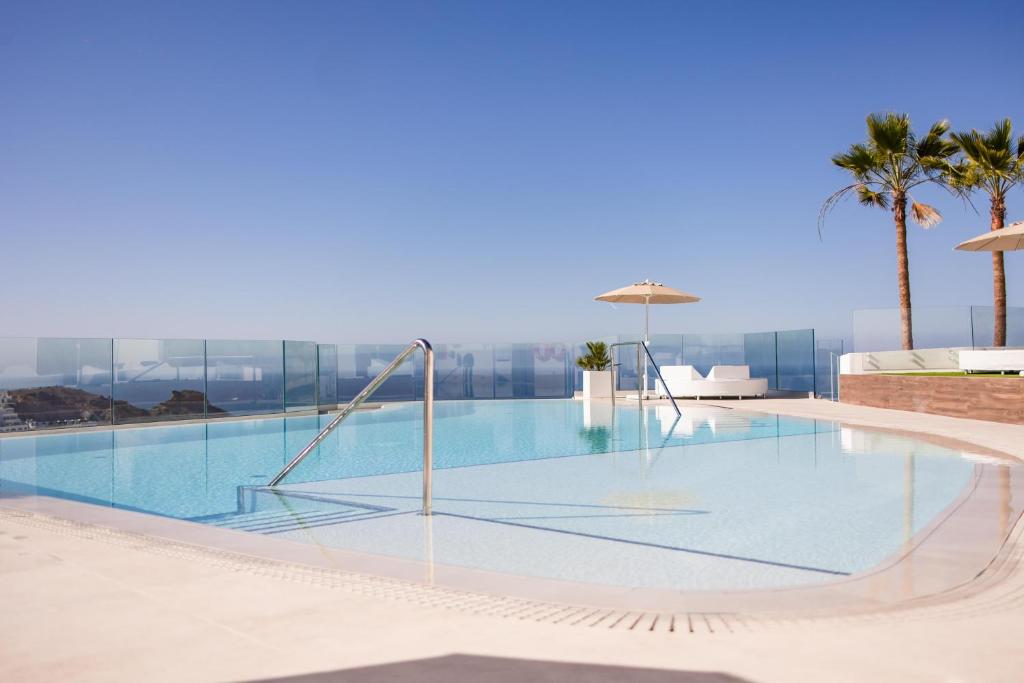 a swimming pool with a slide and palm trees at Servatur Hartaguna - Adults Only in Puerto Rico de Gran Canaria