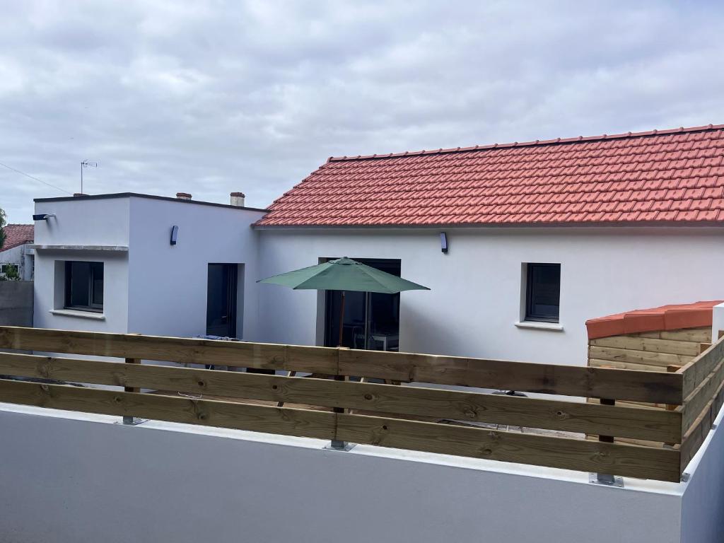 a green umbrella sitting on the side of a white building at Maison de vacances entre forêt et plage in Saint-Jean-de-Monts