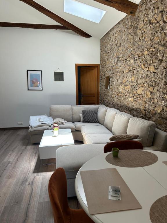 a living room with a couch and tables and a stone wall at Bel Appartement au 2 eme in Aix-en-Provence