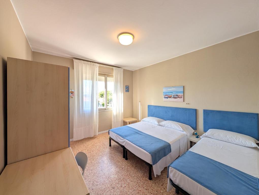 a hotel room with two beds and a window at Alloggi San Marco in Caorle