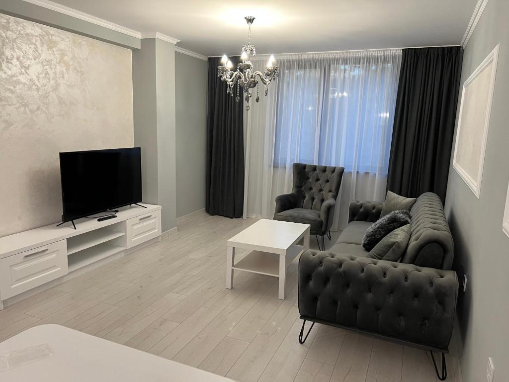 a living room with a couch and a television at ЛУКСОЗНИ АПАРТАМЕНТИ ДАРИС-free parking in Kazanlŭk