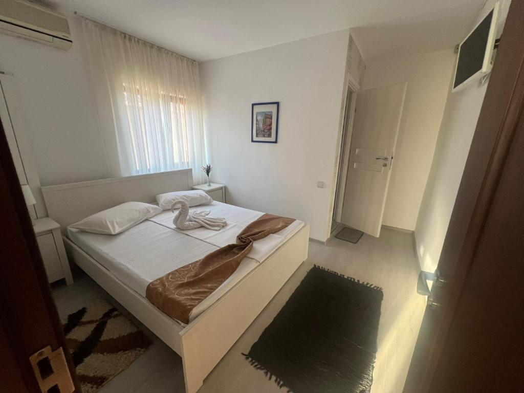 a small white bedroom with a bed and a window at Emmaia Escape Eforie Nord in Eforie Nord
