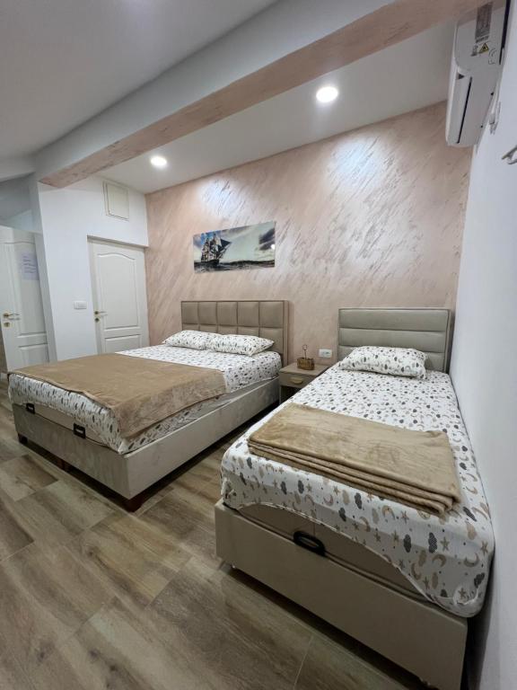two beds sitting in a room with wooden floors at Apartment Tri limuna 3 in Herceg-Novi
