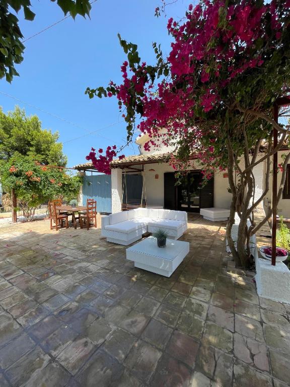 a patio with white couches and a tree with pink flowers at Sunset Kite Village in Marsala