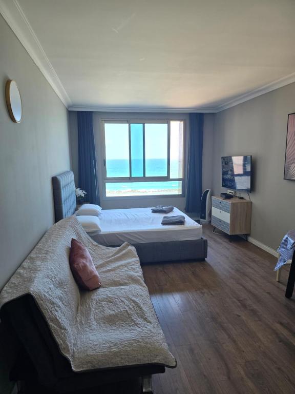 a bedroom with two beds and a couch and a window at Sea Vacation in Haifa