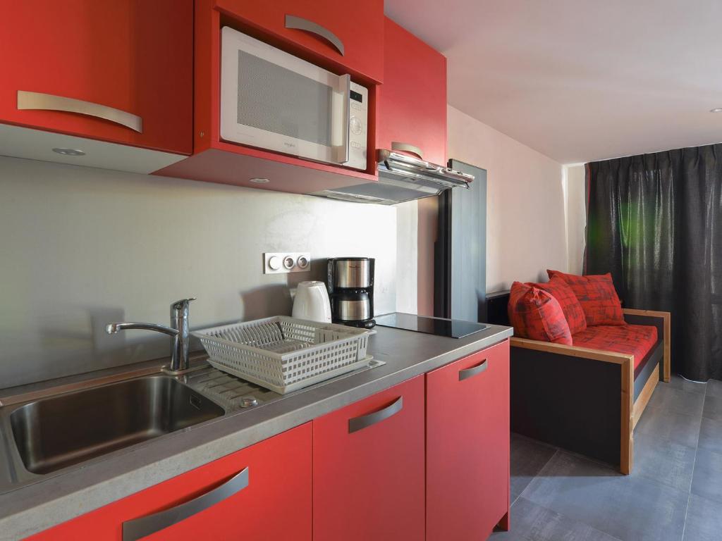 - une cuisine avec des placards rouges, un évier et un canapé dans l'établissement Studio rénové aux Coches · Proche des pistes · Espace bien-être inclus - FR-1-181-1072, à Les Coches