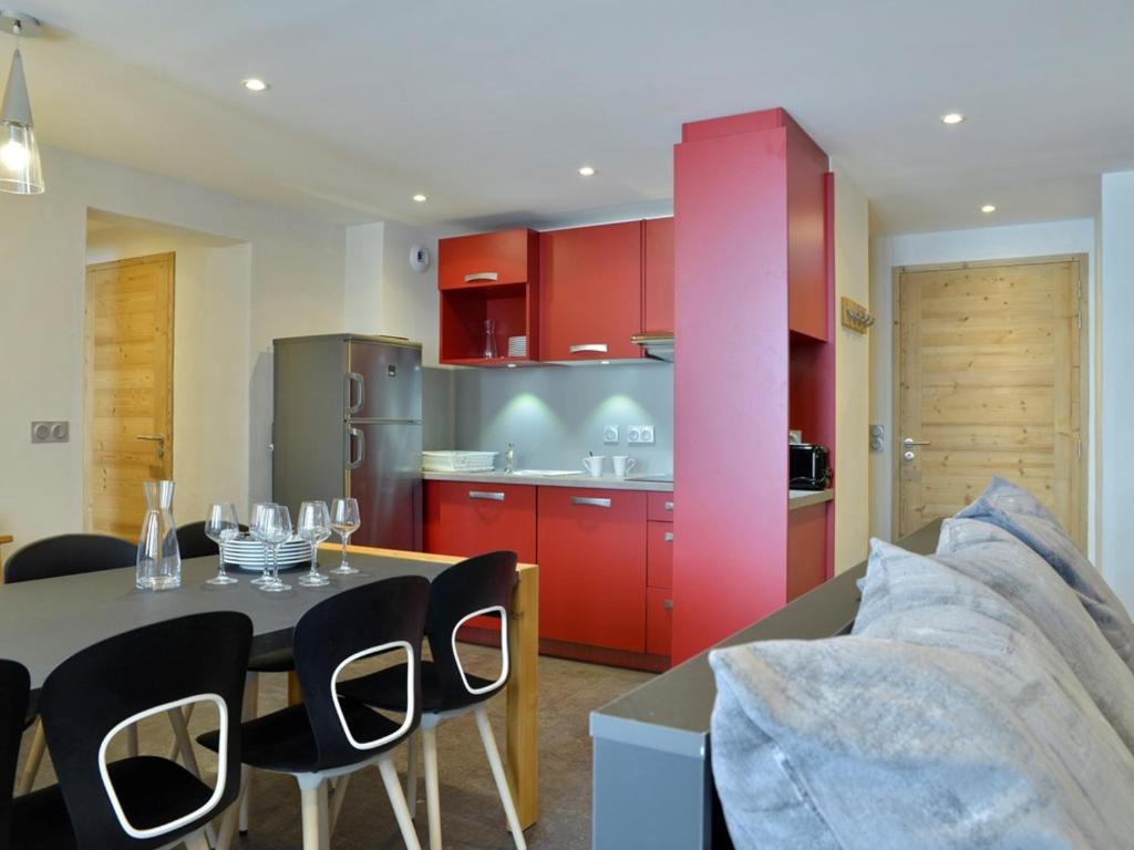une cuisine avec des armoires rouges et une table et des chaises dans l'établissement Appartement rénové proche des pistes avec espace bien-être - FR-1-181-1908, à La Plagne Tarentaise