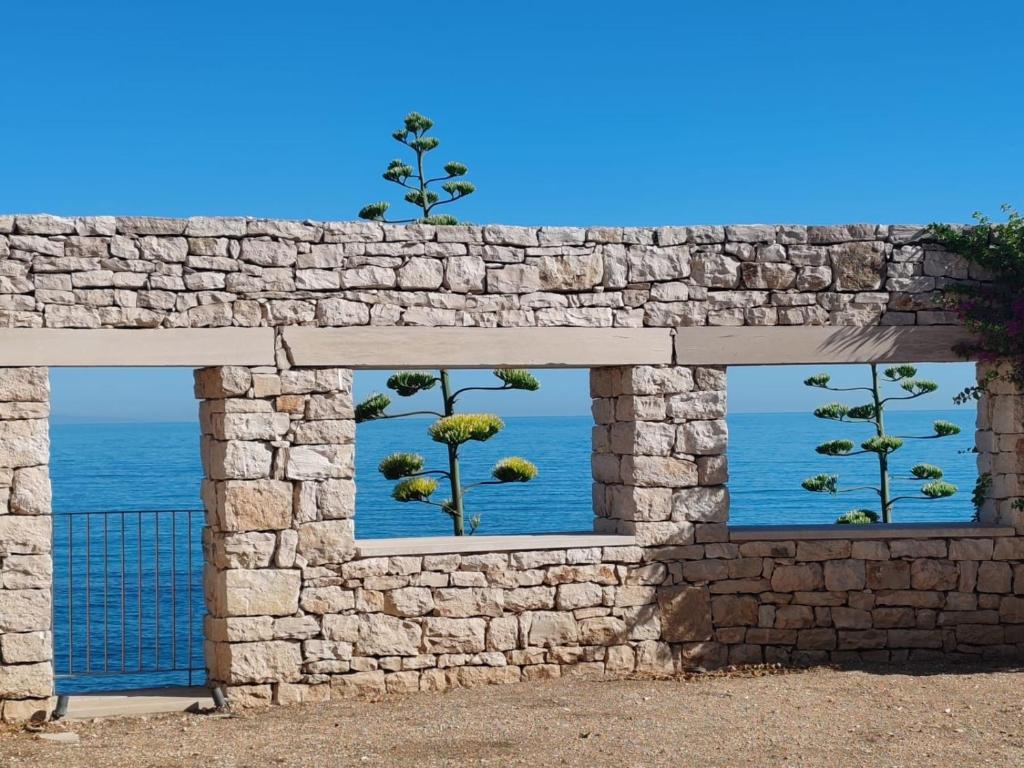 a stone wall with two windows looking out at the ocean at Banfi's villa on the sea in Bisceglie