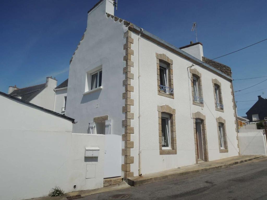 un bâtiment blanc au bord d'une rue dans l'établissement Étel - Maison 115 m², 5 pièces, vue port, 9 pers. - FR-1-479-231, à Étel