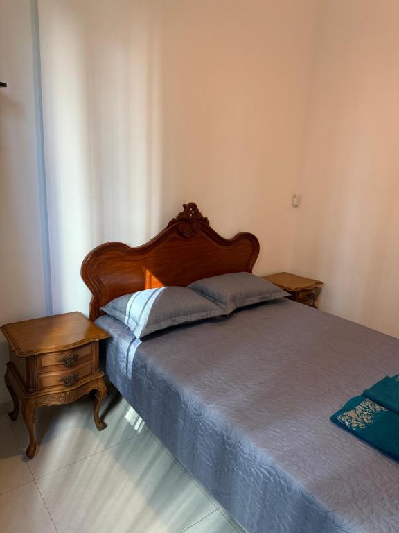 a bedroom with a bed with a wooden headboard and a table at Apartamento Aconchegante em Botafogo in Rio de Janeiro
