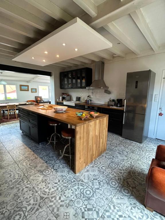 une grande cuisine avec un îlot en bois au milieu dans l'établissement Longère pornicaise avec piscine chauffée, à Pornic