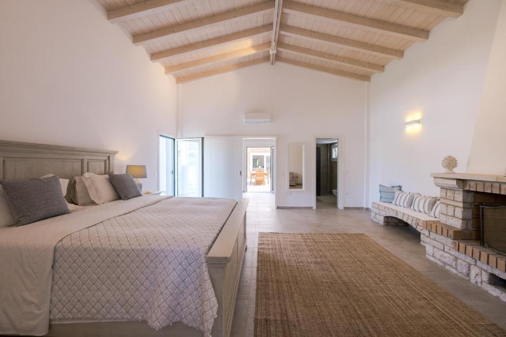 een witte slaapkamer met een groot bed en een open haard bij Villa Botanica in Kassiopi