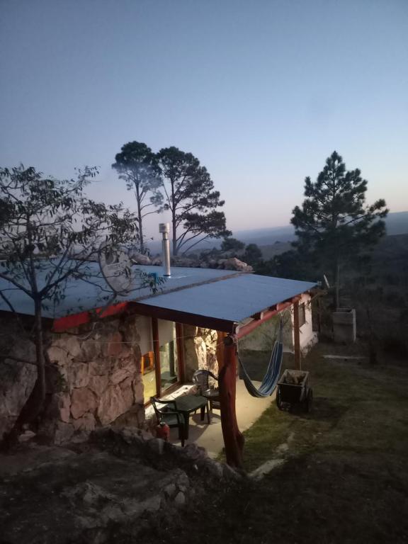 a house with a blue roof with a hammock outside at Las Chuñas in Villa Yacanto