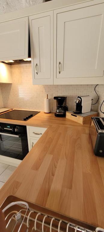 a kitchen with white cabinets and a wooden counter top at Maison de caractère - L'évasion forestière in Baguer-Pican