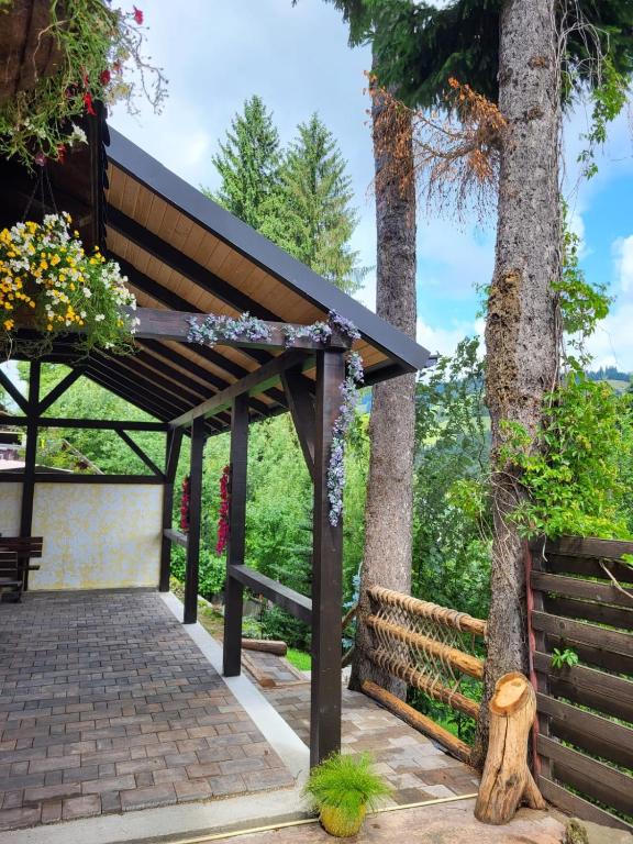 a pergola with flowers on it next to a tree at vila Dariana in Vatra Dornei