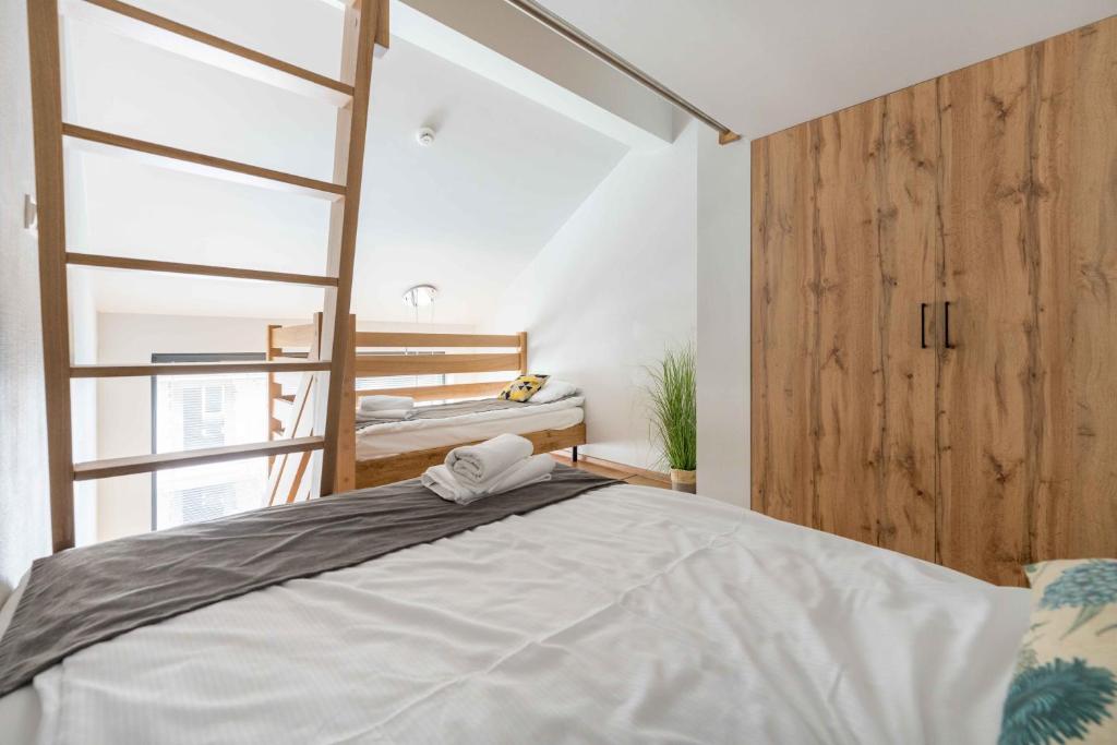 Loft bedroom showing main bed in foreground, wooden bunk bed accessed by ladder, and large wood wardrobe.
