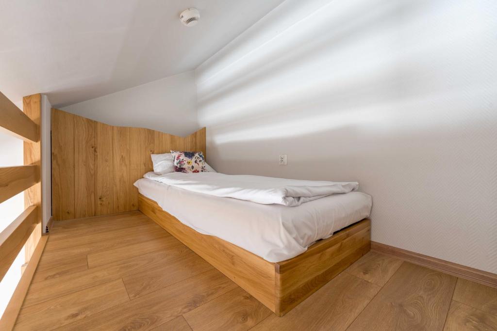Cozy single loft bed with wooden base and headboard, floral cushion, soft daylight casting shadows.