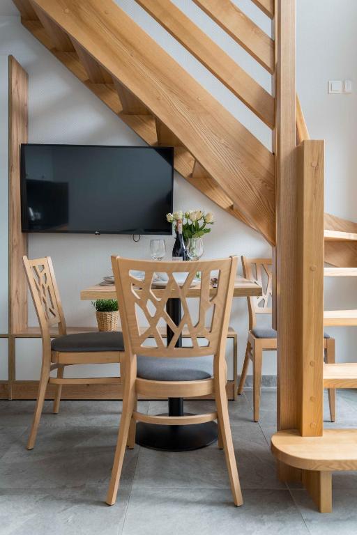 Cozy dining nook under wooden staircase with table set, chairs and wall-mounted TV.
