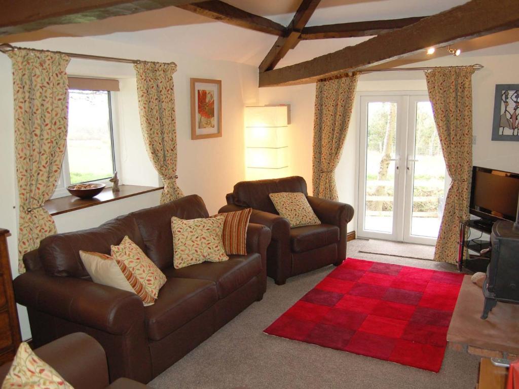 a living room with two leather couches and a television at Nuthatch Cottage in Westward