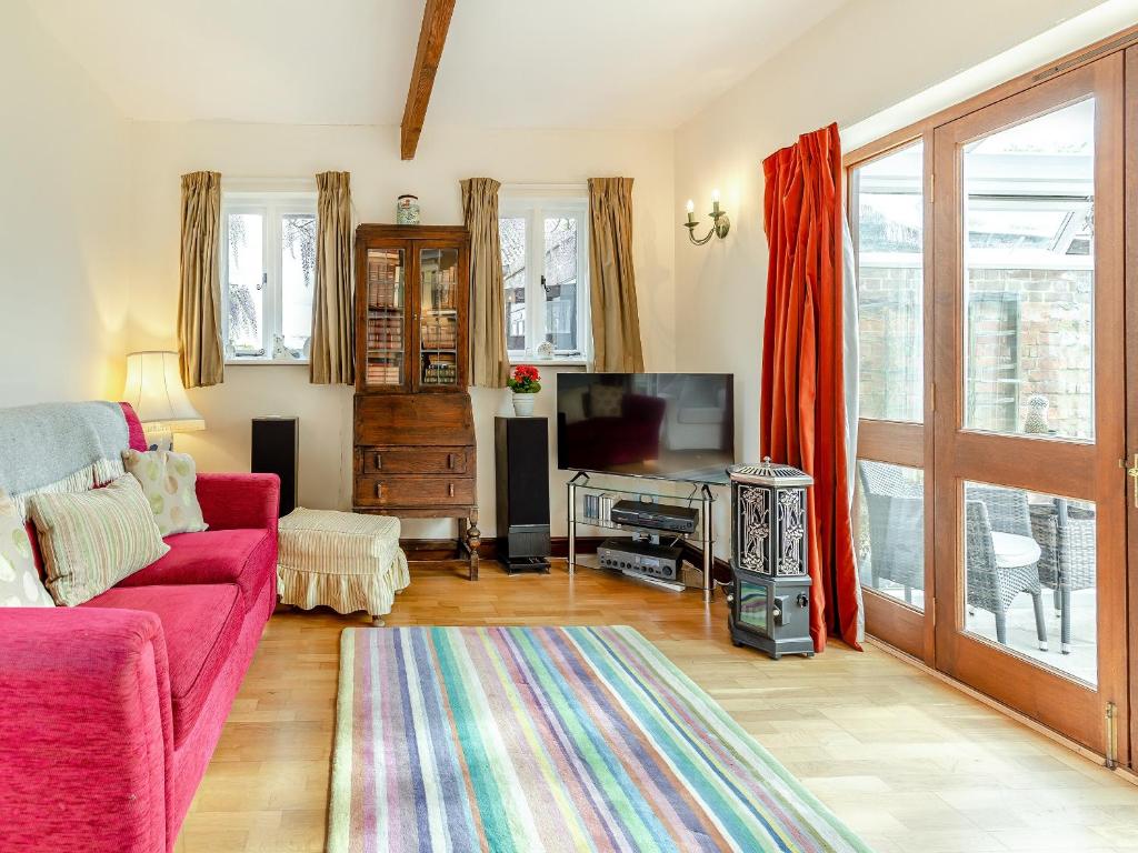 a living room with a red couch and a tv at The Coach House in Aldington