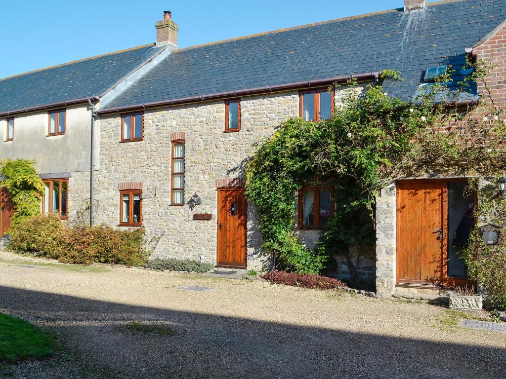 a brick house with wooden doors on a street at Carters Cottage in Puncknowle