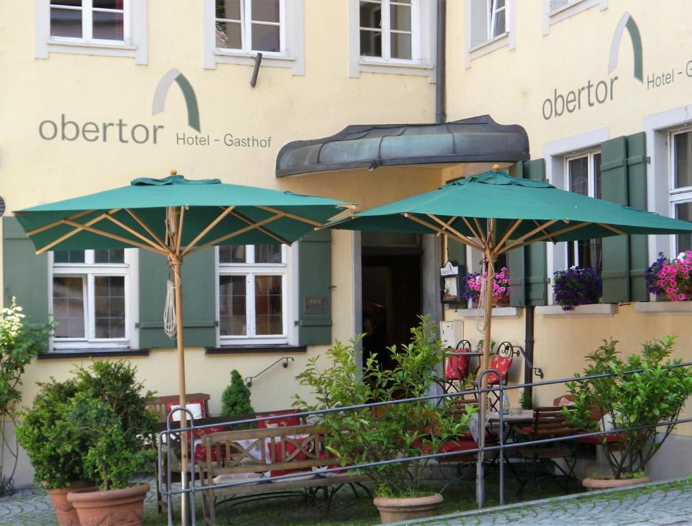 two tables and umbrellas in front of a building at Hotel Obertor in Ravensburg