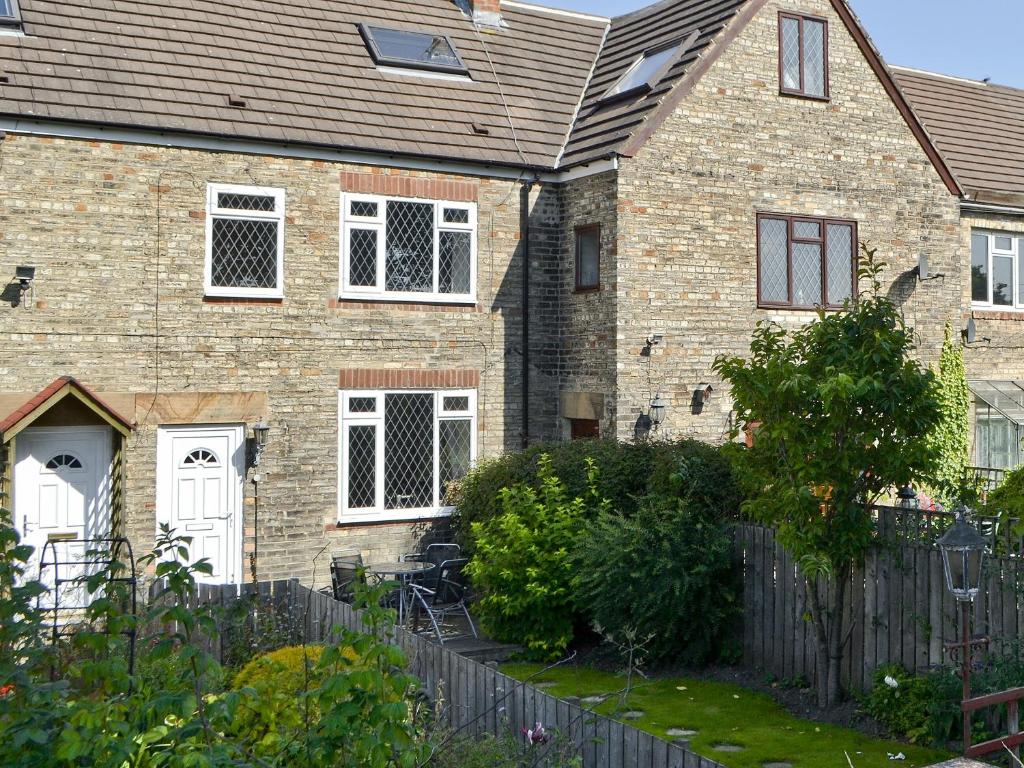 a brick house with a fence in front of it at Isabella Cottage in Heddon on the Wall