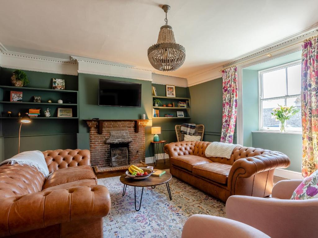 a living room with leather couches and a fireplace at The Retreat - M in Burton Bradstock
