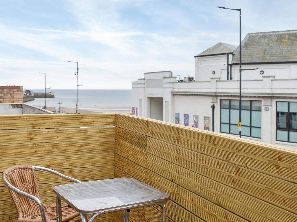 una mesa y una silla en un balcón con vistas al océano en South Side - Apartment, en Bridlington