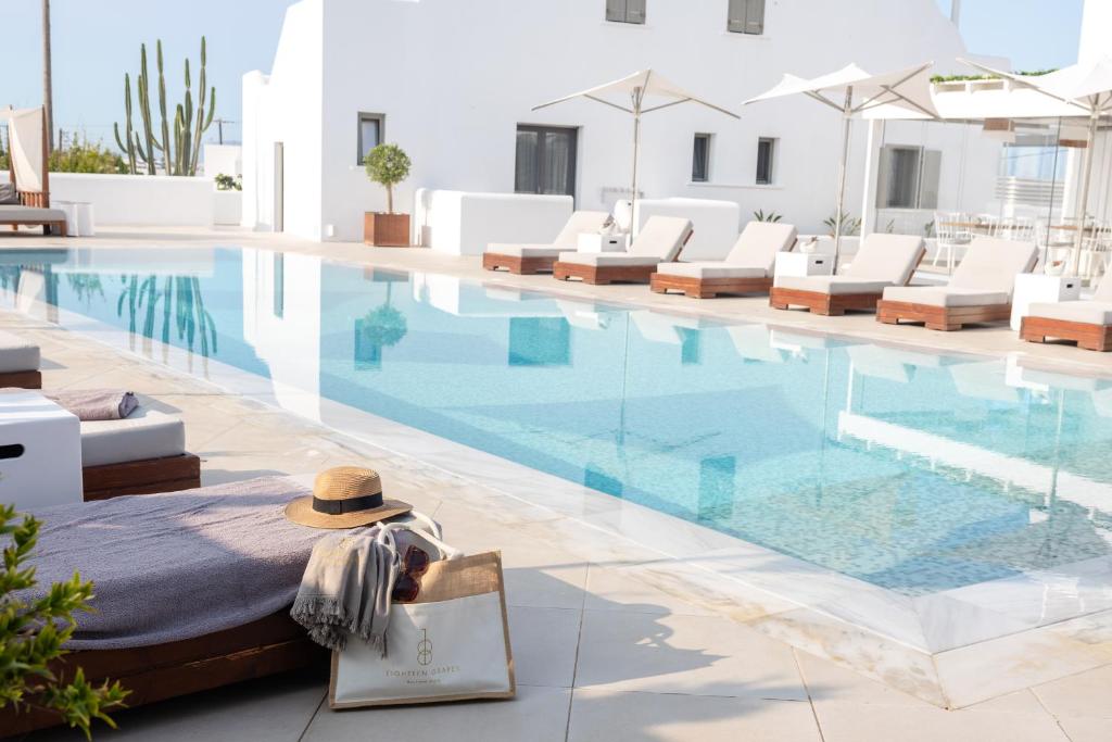 Una piscina con tumbonas y un sombrero al lado. en 18 Grapes Hotel, en Agios Prokopios